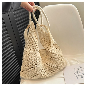 Close-up of beige woven tote bag showing intricate crochet texture and long tassels