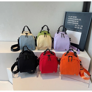 Selection of vibrant minimalist crossbody bags displayed on a tiered shelf with rope handles