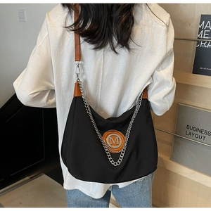 Detail of the large black nylon crossbody bag with silver chain and brown leather strap