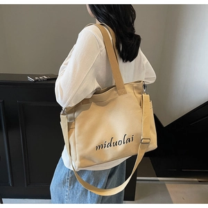 Detailed shot of a beige canvas tote bag with adjustable strap and side pocket detail