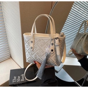 Detail of a beige geometric tote bag with fringe charm and silver hardware accents