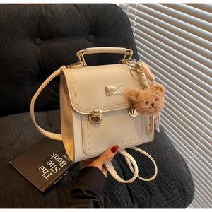 Detail of beige leather mini backpack with gold twist lock and cute teddy bear charm
