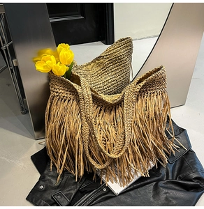 Détail macro du tissage en paille et des longues franges sur ce grand sac de plage