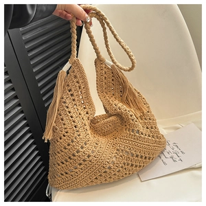Detail of bohemian khaki woven tote bag featuring hollow diamond patterns and tassel accents