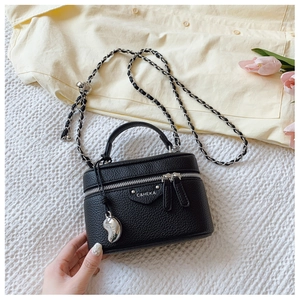 Detailaufnahme der schwarzen Box-Bag aus Narbenleder mit Silberkette und Metallanhänger