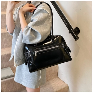 Detailed view of black patent leather boston bag with silver zippers and buckle accents