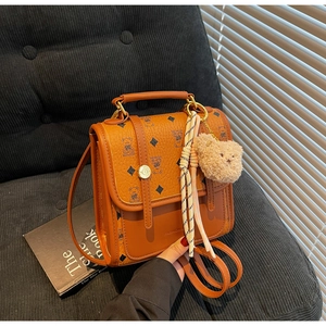 Brown leather backpack with bear print, bear charm, and striped scarf detail on sofa