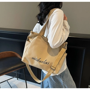 Detail of off-white canvas tote bag with black lettering print and adjustable strap