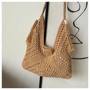 Close-up of handmade crochet straw tote bag with fringe tassels and woven texture details