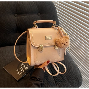 Detail of pink leather backpack with gold hardware, wave stitching and plush bear charm