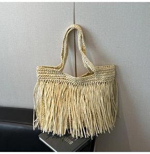 Détail du sac de plage en paille bohème avec de longues franges et texture tissée