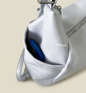 Détail de la poche latérale du cabas bleu clair montrant la capacité avec un téléphone