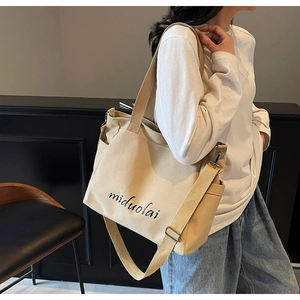 Side view of beige canvas tote bag with adjustable strap and miduolai script print