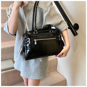 Detail of glossy black patent leather shoulder bag with silver metallic hardware buckle