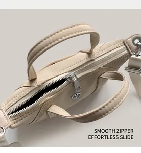 Detail view of smooth silver metal zipper and M-letter charm on beige nylon handbag