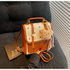 Close-up of beige and caramel tote bag featuring bear prints, diamond texture and plush charm