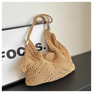 Close-up of beige woven tote bag with diamond crochet patterns and tassel details