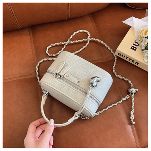 Detail der weißen Box-Tasche aus genarbtem Leder mit Herzanhänger und Kettenriemen