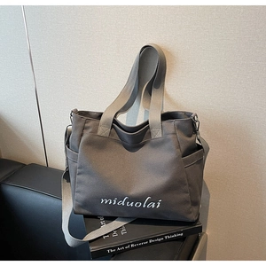Close-up of grey canvas tote bag with adjustable strap and side pockets for commuting