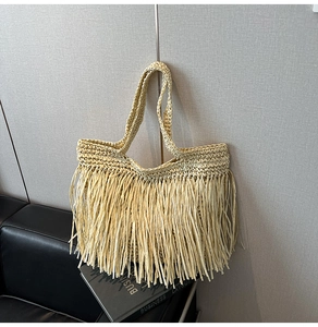 Détail du sac de plage en paille avec longues franges et texture tissée à la main