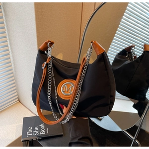 Close-up of crescent shoulder bag with metal M logo, orange trim and layered silver chains