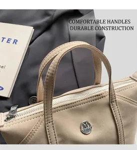 Close-up of beige nylon tote bag with round M logo and zipper closure for office work