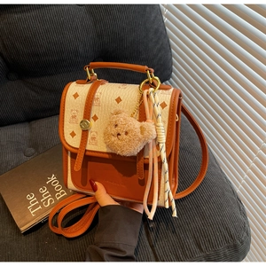 Detail of mini handbag with brown bear print, metal chain, and cute plush charm accessory