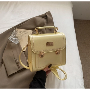 Close-up of yellow leather shoulder bag with gold buckles and white stitching details