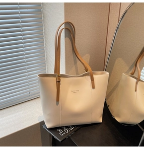Détail du sac cabas minimaliste crème avec bandoulières marron et logo imprimé élégant