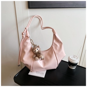 Close-up of pink glossy pleated crescent bag with cute plush bear charm detail