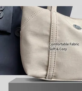 Detail shot of beige canvas bag texture with precise stitching and metal badge
