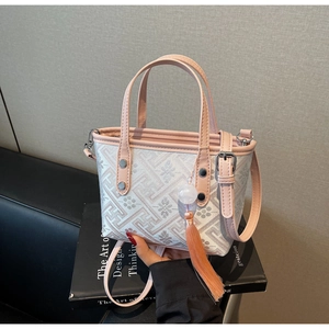 Detailed view of pink leather trim, floral print fabric and tassel charm on bucket bag