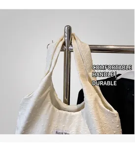 Detailed shot of cream canvas tote bag showing textured surface and Nuo si Man brand label