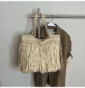 Détail de la texture tissée et des longues franges de ce sac cabas en paille beige