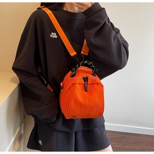 Close-up of orange waterproof nylon mini backpack with woven handle and dual zippers