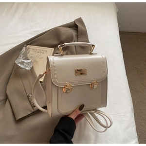 Detail of a cream vintage messenger bag with gold hardware on a stylish lifestyle background