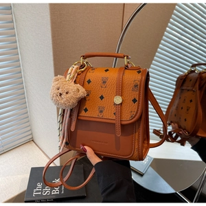 Detail of brown leather backpack with bear pattern and golden twist lock closure