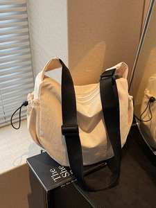 Minimalist off-white canvas crescent bag with black wide adjustable shoulder strap