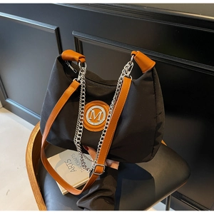 Detail of black nylon crescent bag with brown leather handles and silver M logo