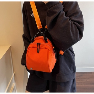 Detail shot of mini orange canvas backpack with black zippers and woven rope handle