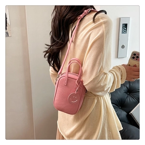 Detailed back view of pink mini crossbody bag with litchi texture and smiley pendant