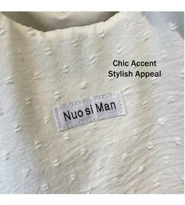 Detailed macro view of white textured canvas fabric and stitched brand label on tote bag