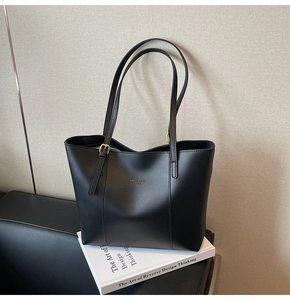 Vue détaillée du sac cabas noir avec lettrage doré et bandoulière à boucle