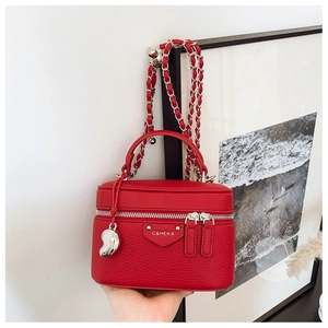 Detail der roten Box-Tasche aus genarbtem Leder mit Herzanhänger und Gliederkette