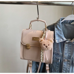 Dettaglio zaino in pelle PU rosa chiaro con fibbia dorata e ciondolo orsetto marrone