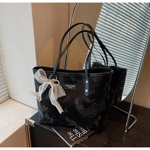 Detail der schwarzen Handtasche mit Marmorstruktur, Netzschleife und Perlenanhänger