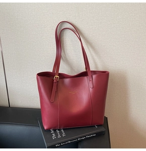 Détail du sac cabas bordeaux mat avec marquage doré et boucles de réglage latérales