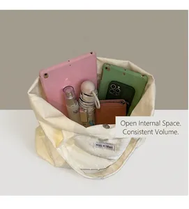 Detail view of white canvas tote bag spacious interior holding tablet, umbrella and phone