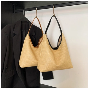 Detail of hand-woven straw shoulder bags with black and brown PU leather handles