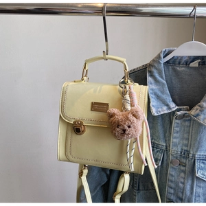 Dettaglio della borsa gialla in pelle PU con fibbia dorata e ciondolo a forma di orso